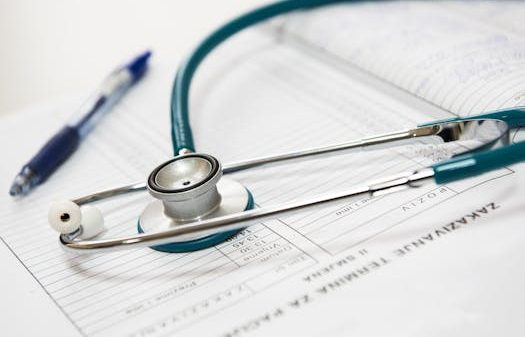 A stethoscope and pen resting on a medical report in a healthcare setting.