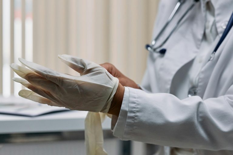 Close-up of a doctor wearing latex gloves, preparing for a medical procedure in a clinic.